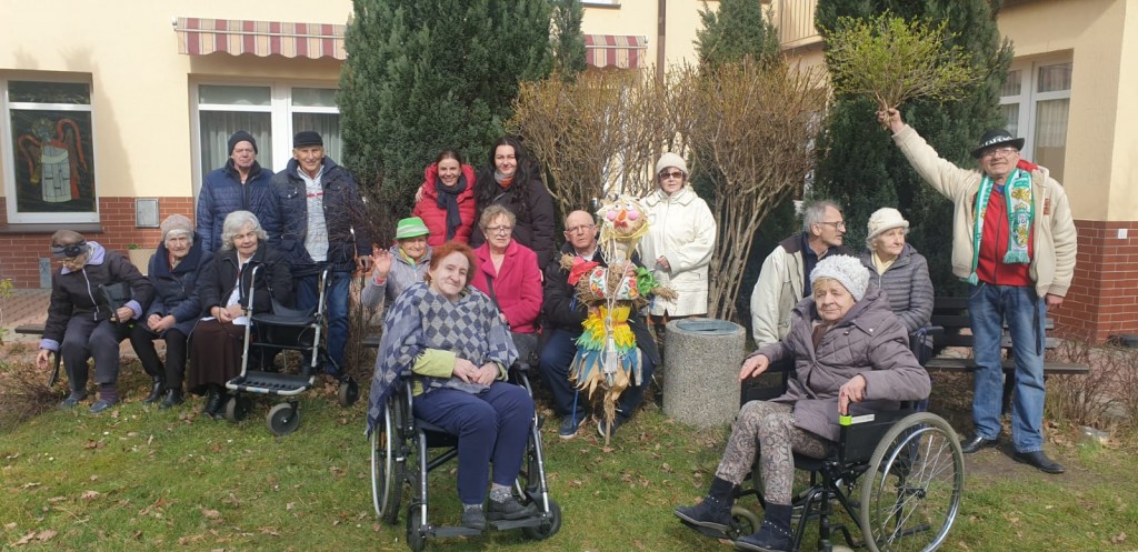 grupa seniorów w ogrodzie dps pozuje do zdjęcia z marzanną